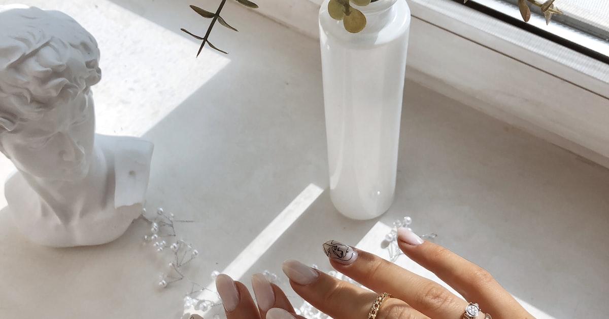 Manicured hands resting on a table beside fresh flowers