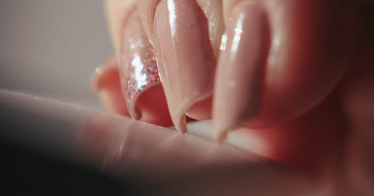Birthday nails with glitter embellishments shown on a hand