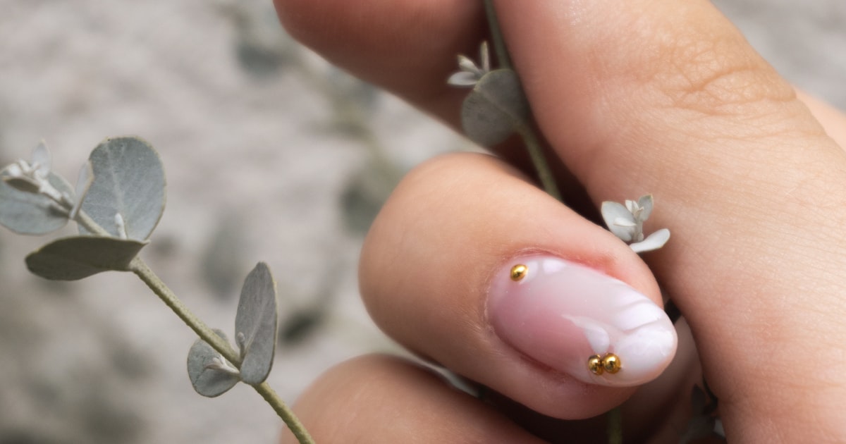 Natural builder gel nails holding a delicate plant stem