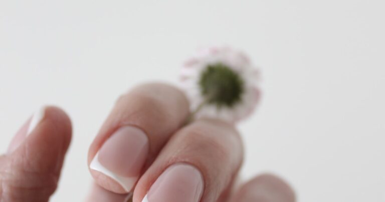French tip nails 2026: classic white-tip manicure holding a small flower