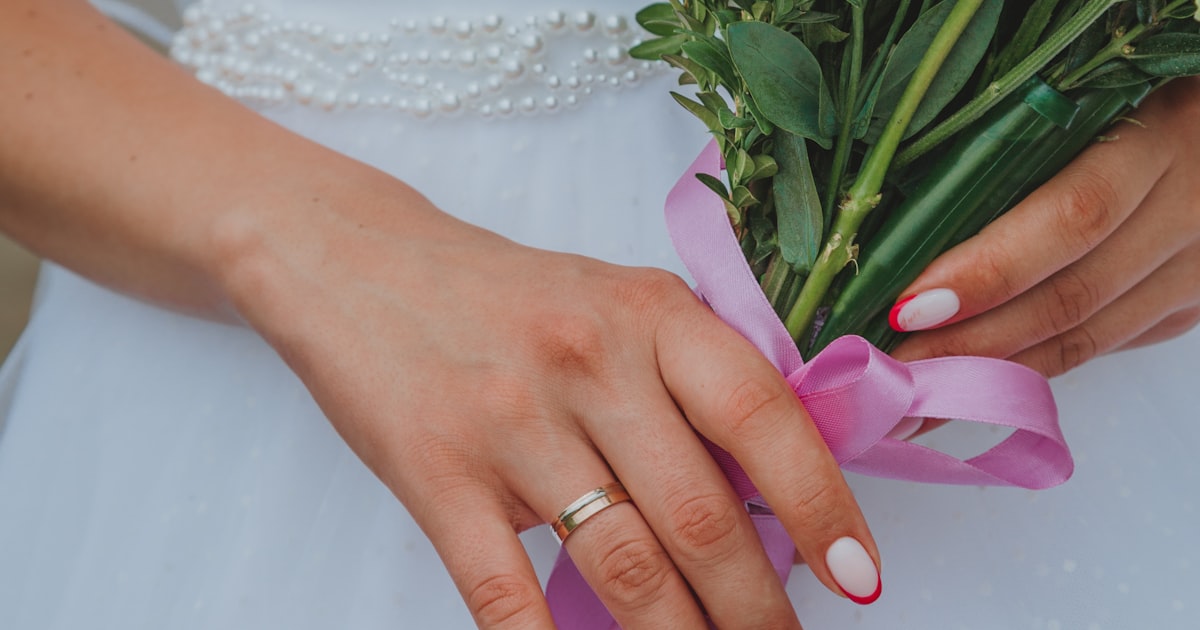 Milky white nails shown holding a bouquet of flowers