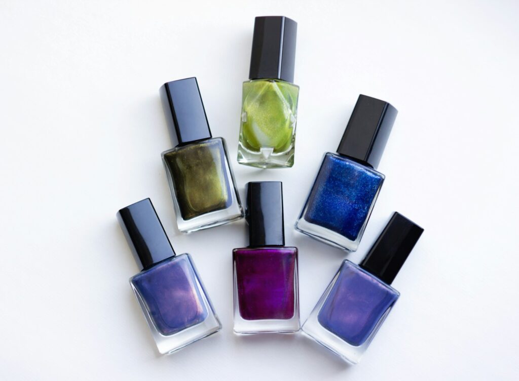 Five colorful nail polish bottles including purple shades lined up