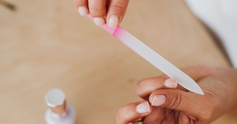 Filing natural nails with a glass file at a home table after acrylic removal