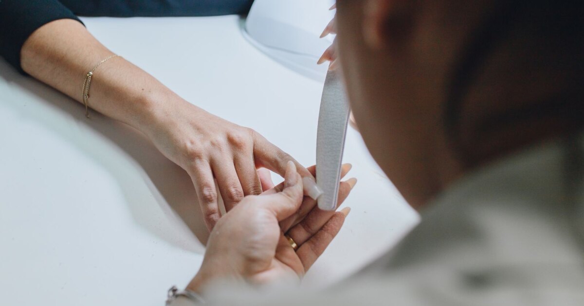 Nail technician filing a client nail, the safer choice when removal should not be done at home