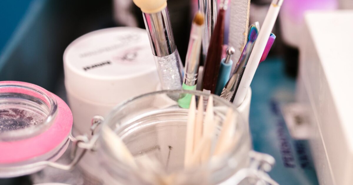 Nail tools including files, brushes and wooden cuticle sticks in a jar
