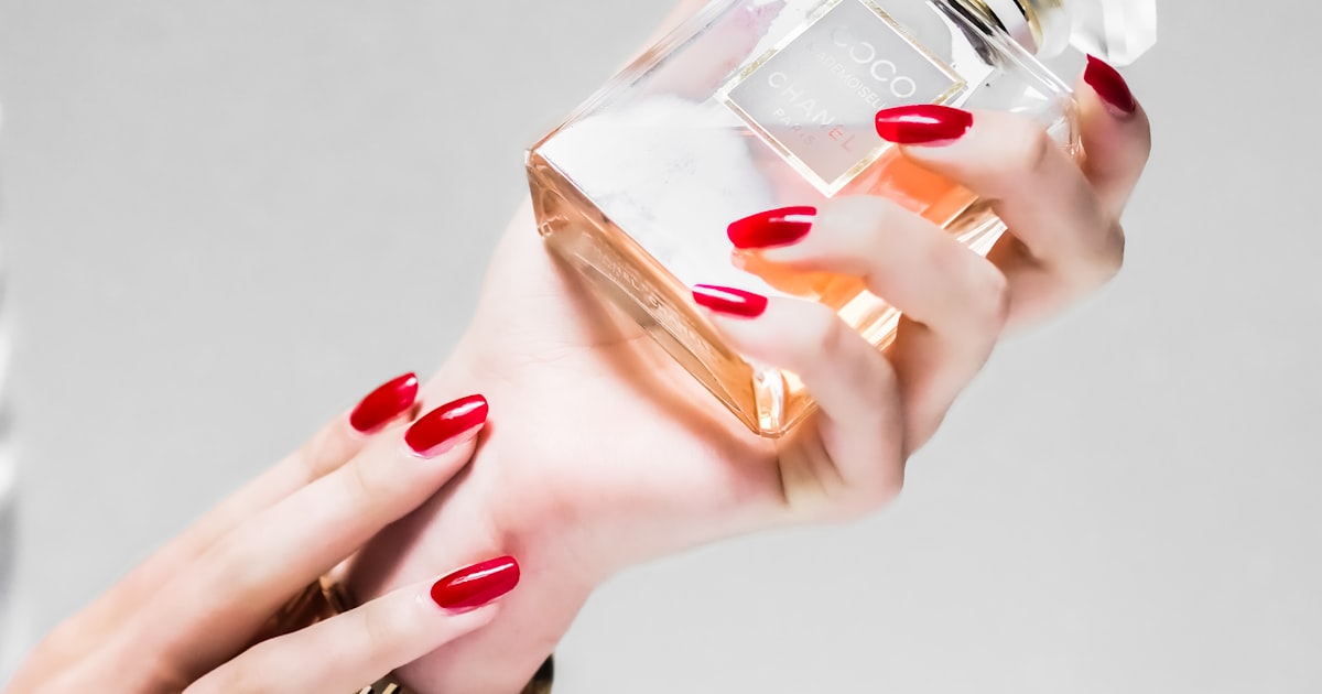 Stiletto nails holding a small glass bottle, showing nail length and taper