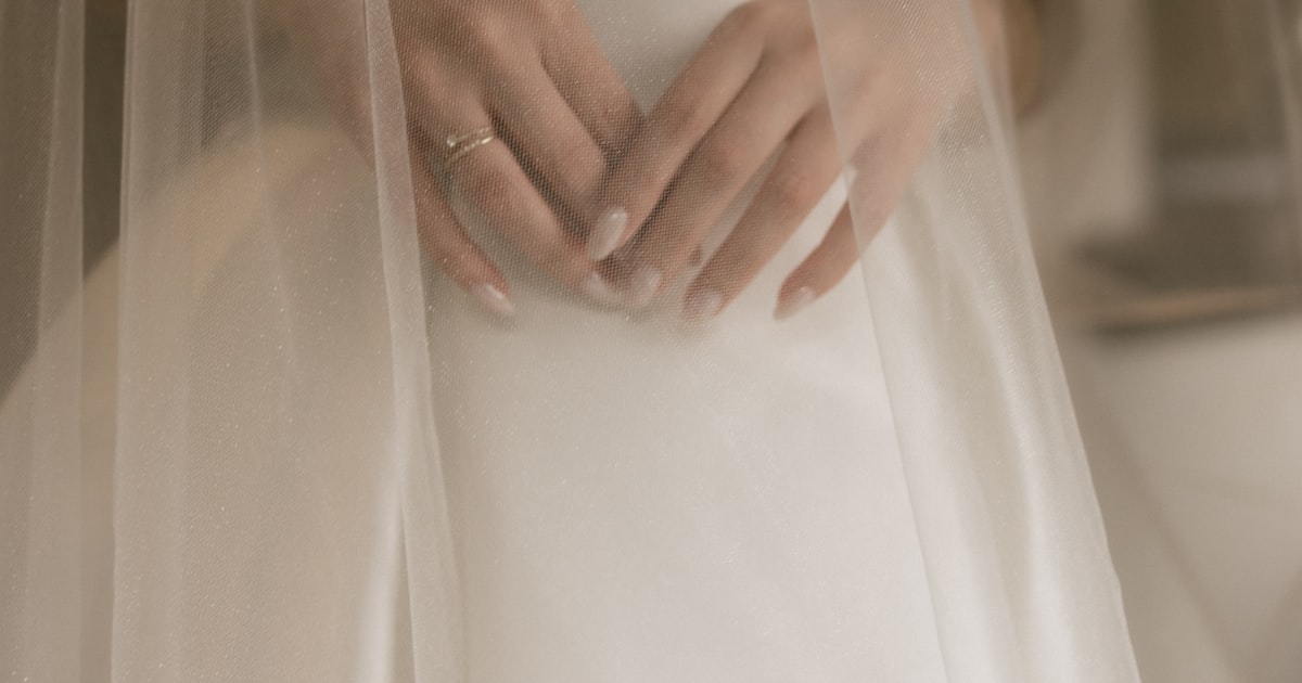 Bride's hands clasped together showing wedding nails and ring