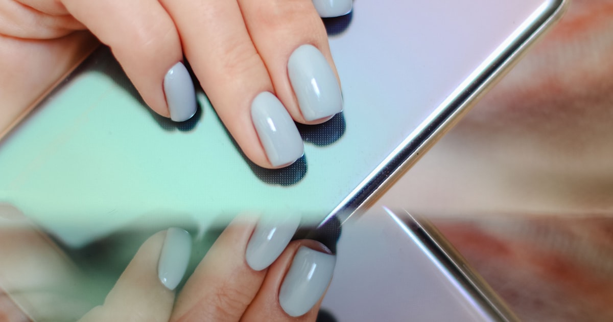 Blue nails visible while holding a phone