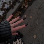 Deep aubergine fall nail polish on square nails against autumn leaves