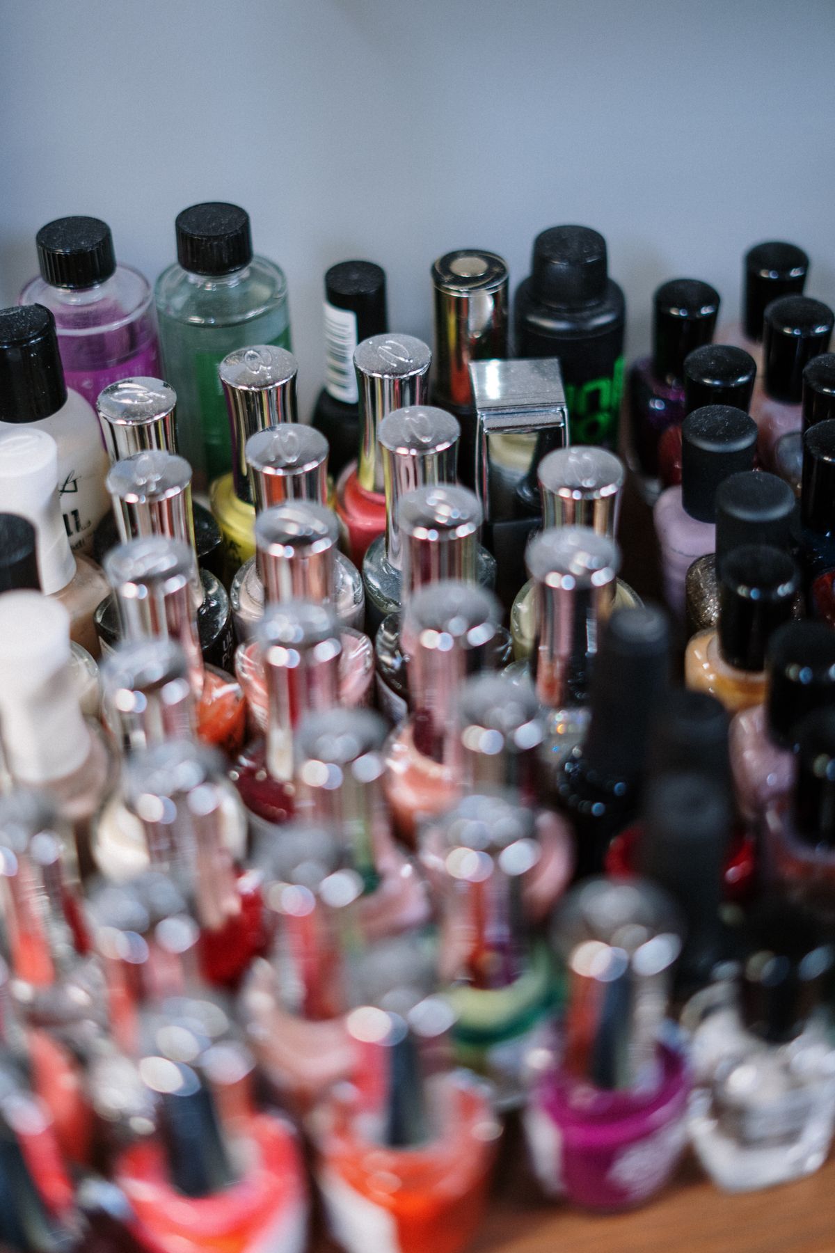 A large collection of nail polish bottles crowded together on a shelf
