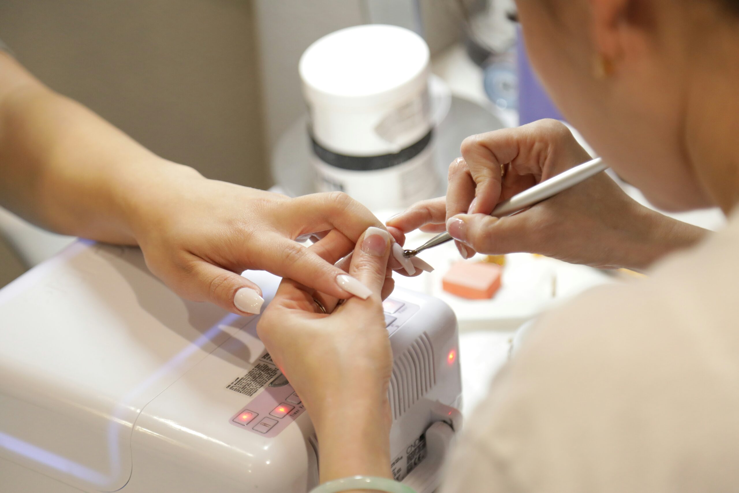 Nail technician applying gel polish during a salon gel nail manicure appointment