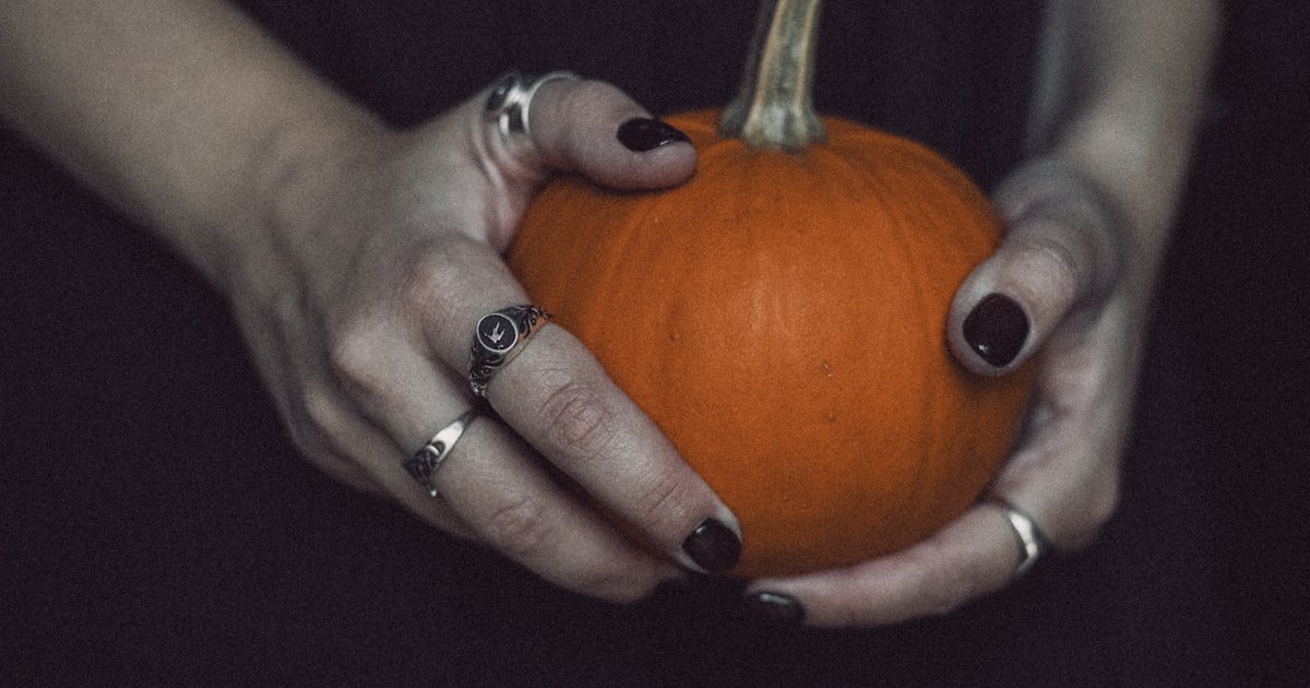 Halloween nails 2026 shown holding a small pumpkin
