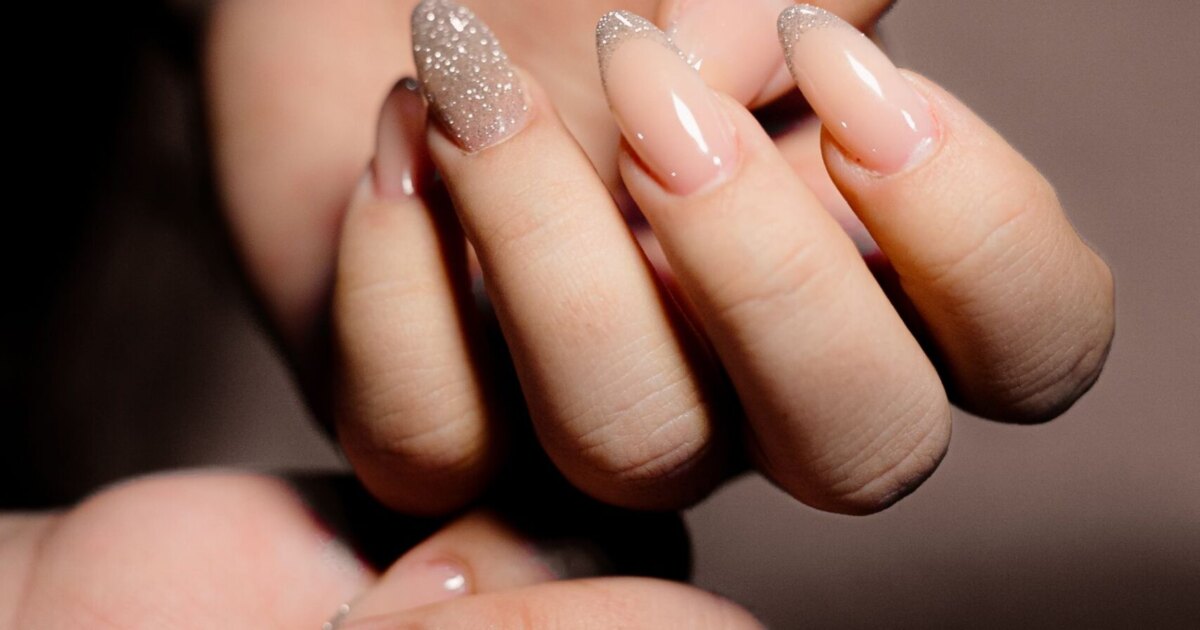 Almond nail shapes for chubby fingers: tapered nude manicure on two hands in warm light