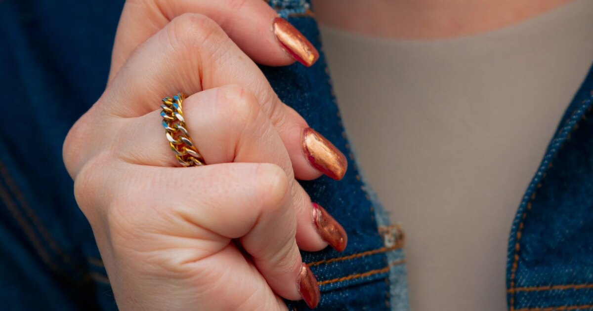 Gilded copper metallic nails against a denim jacket