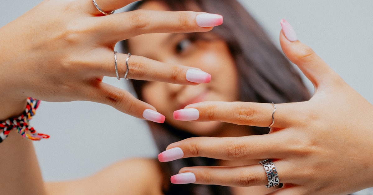 Manicured hand with rings showing soft gradient ombre dip powder nails