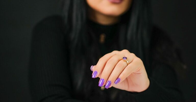 Purple nail designs: glossy lilac manicure with an amethyst ring on a dark background