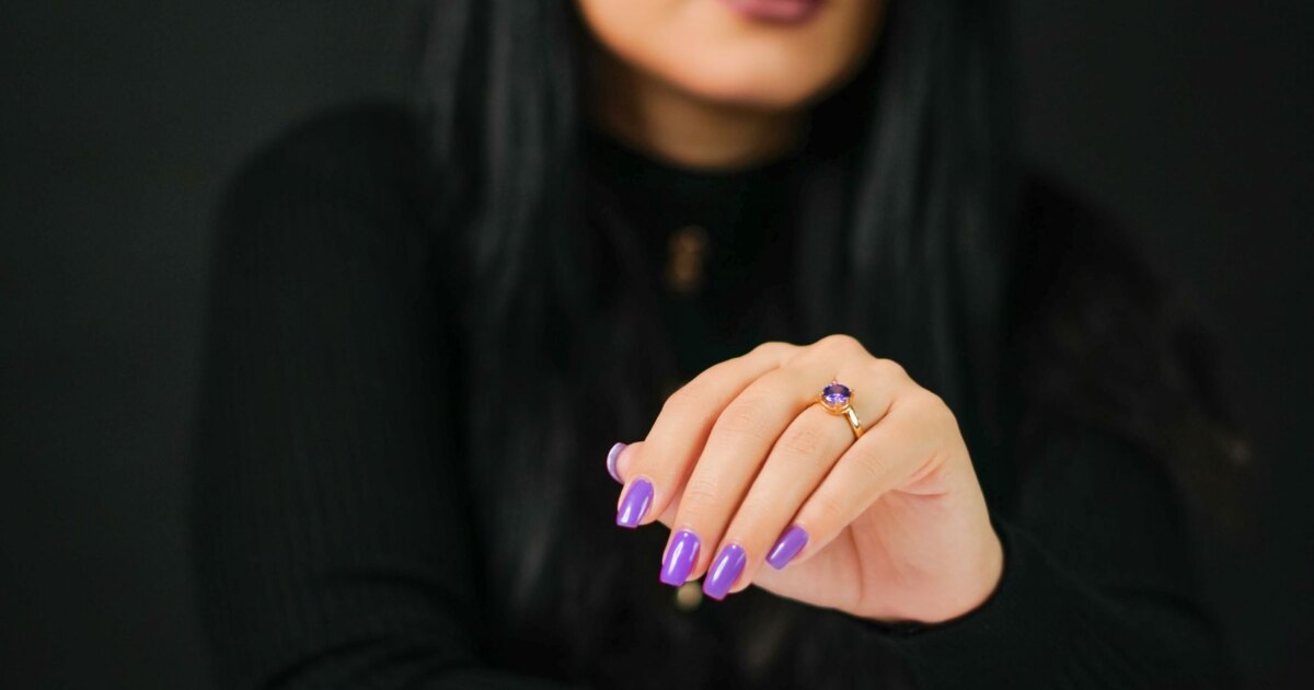 Purple nail designs: glossy lilac manicure with an amethyst ring on a dark background