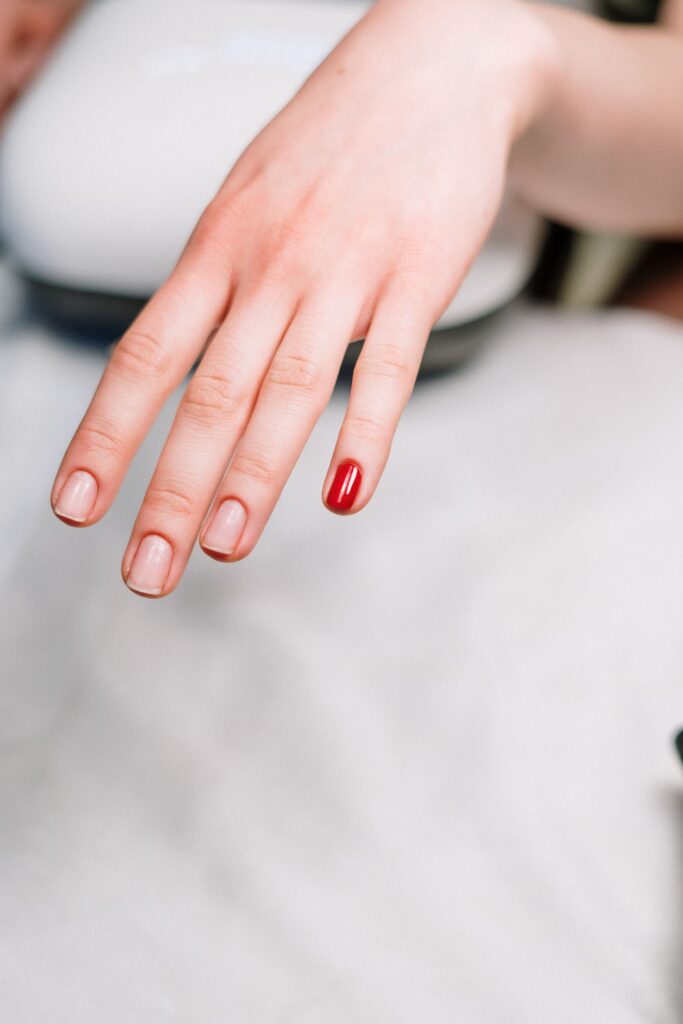 Very short natural nails with a single red accent nail, showing about 2mm of free edge