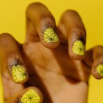 Short natural nails with black spider web nail art on neon yellow polish